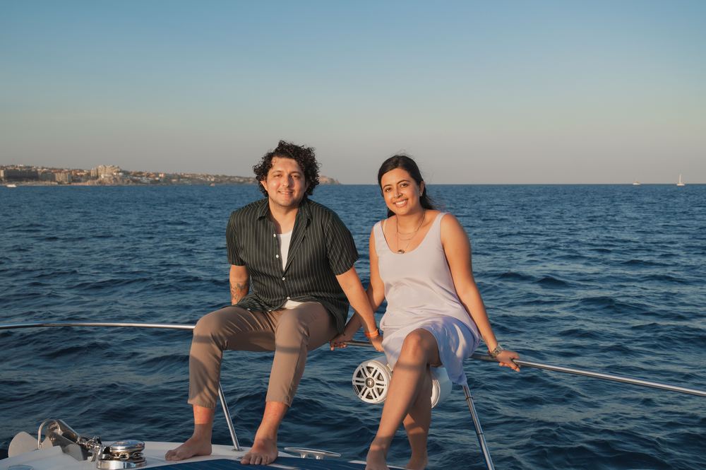 A couple sitting on the bow of a yacht at sunset