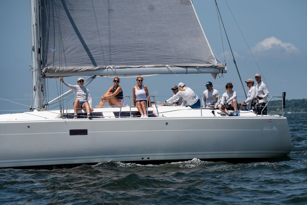 A full racing crew sitting out on the rail of a yacht under sail