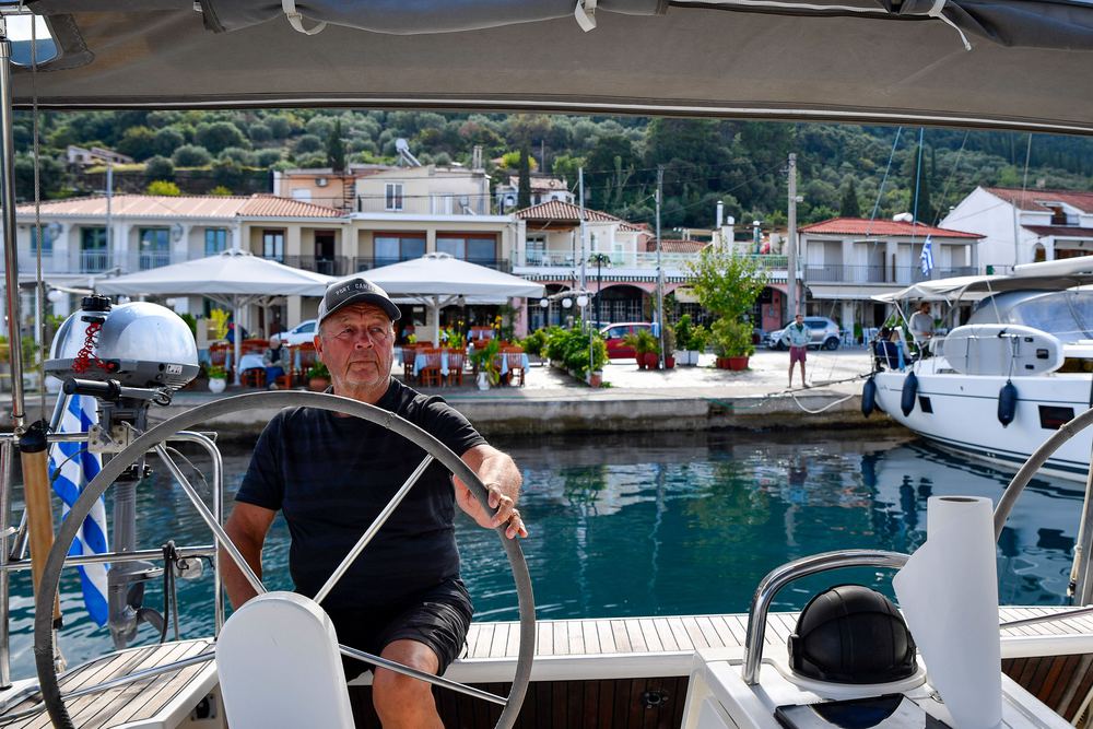 An older skipper at the wheel, alongside in a harbour