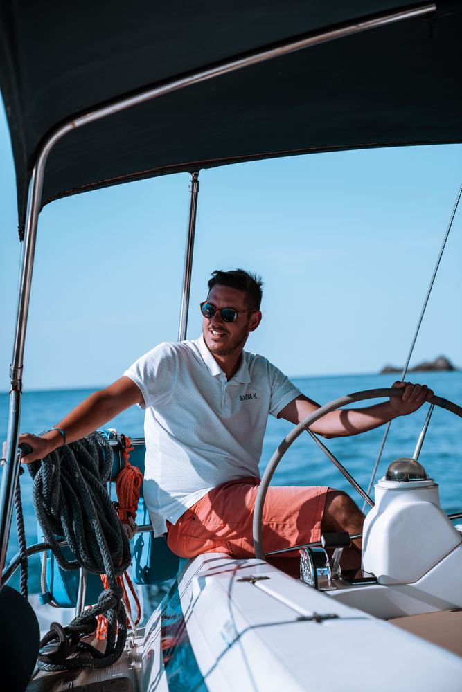 A young sailor at the helm of a yacht in bright sun