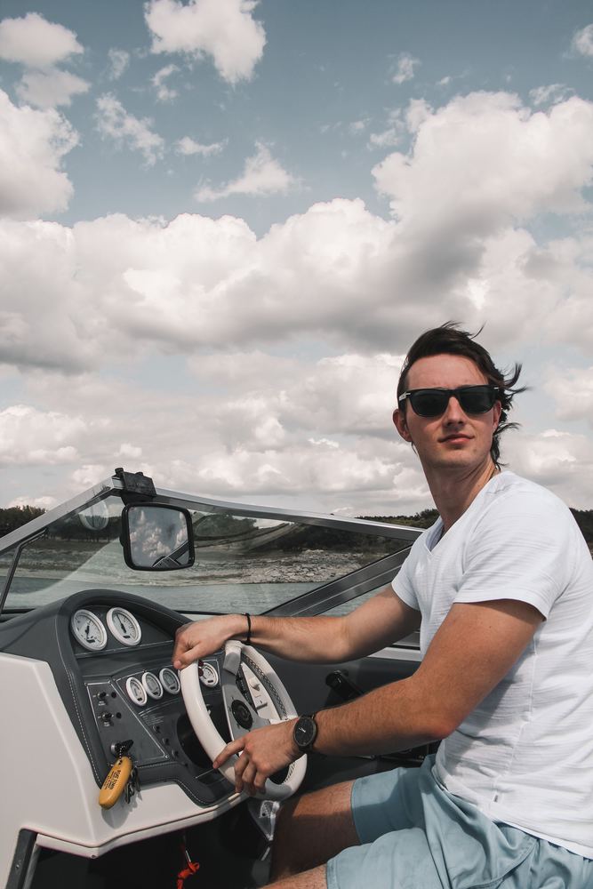 A man driving a powerboat under a big cloudy sky